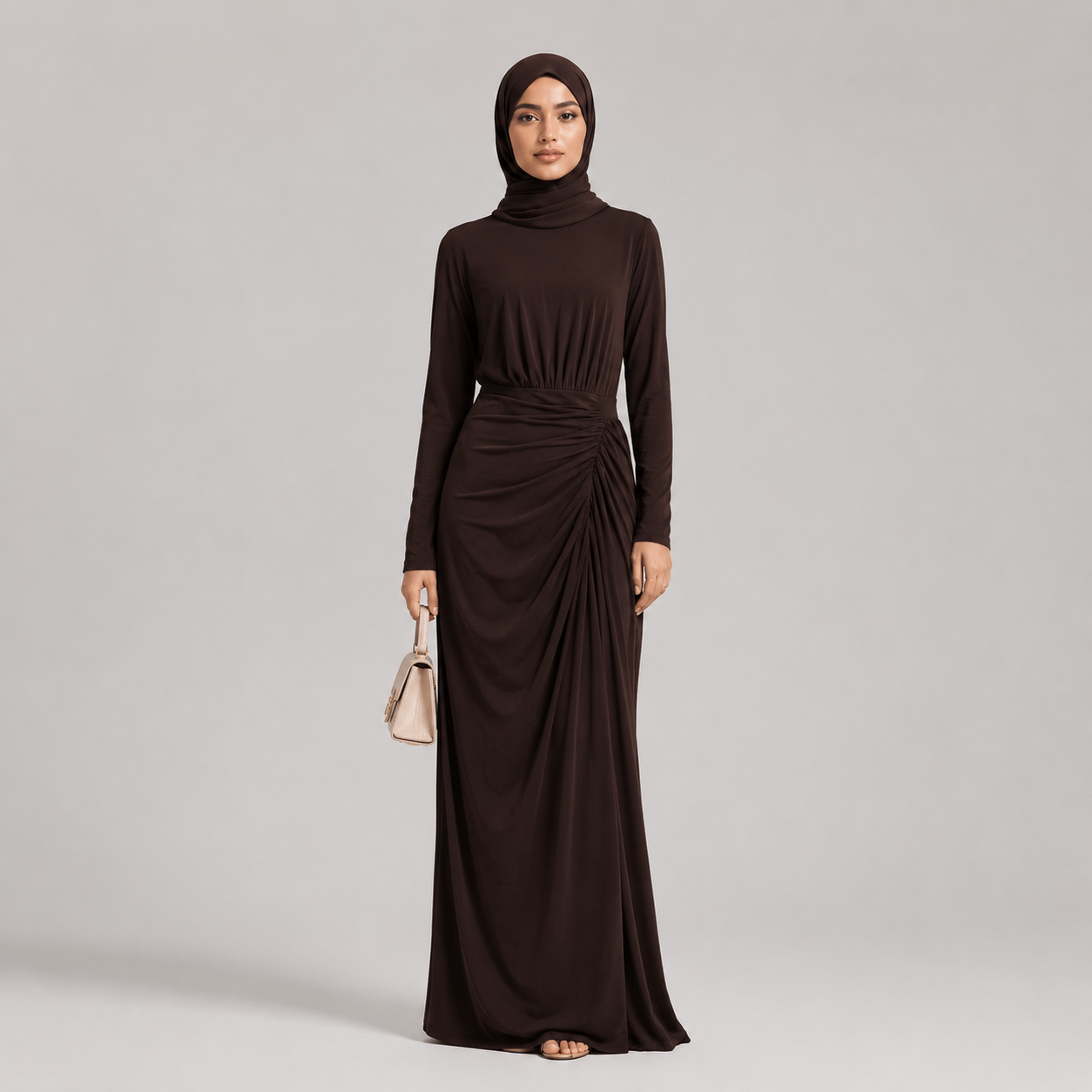 Woman wearing a long brown dress with a matching hijab on a gray background