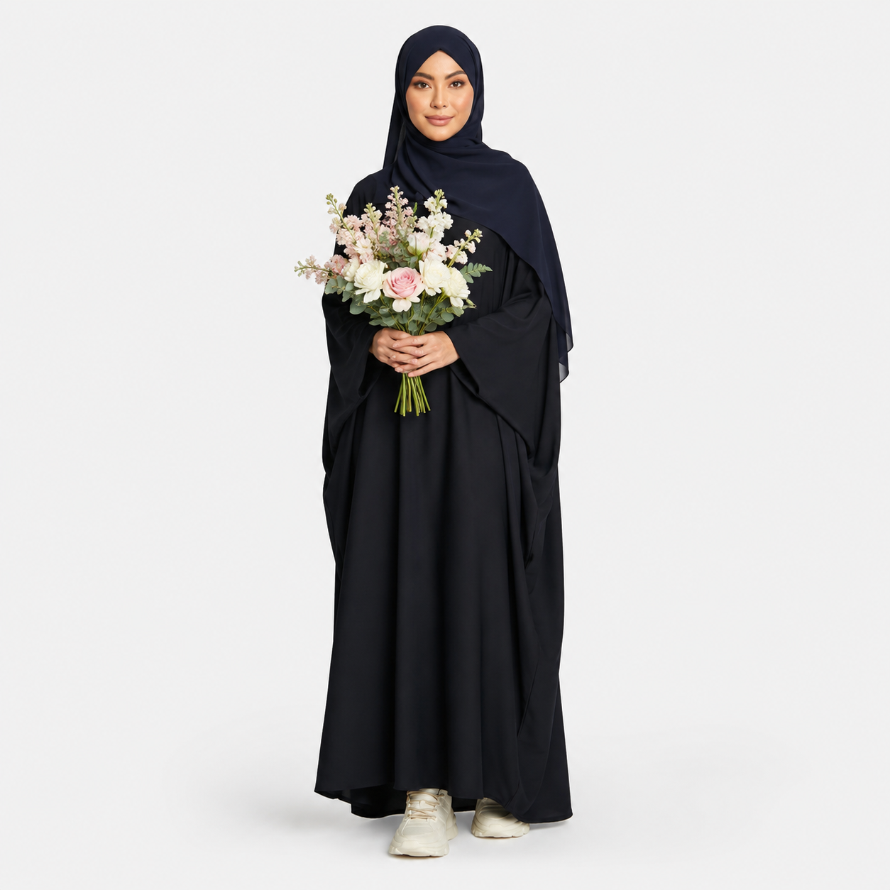 Woman in a black abaya holding flowers on a white background