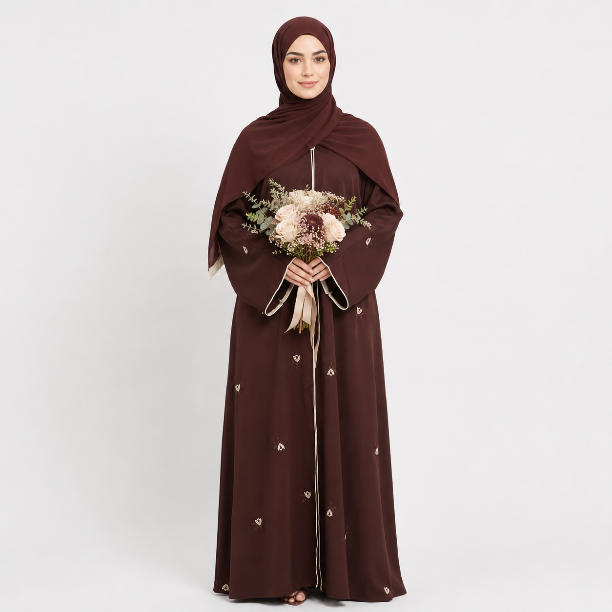 Woman wearing a brown abaya holding a bouquet of flowers on a white background