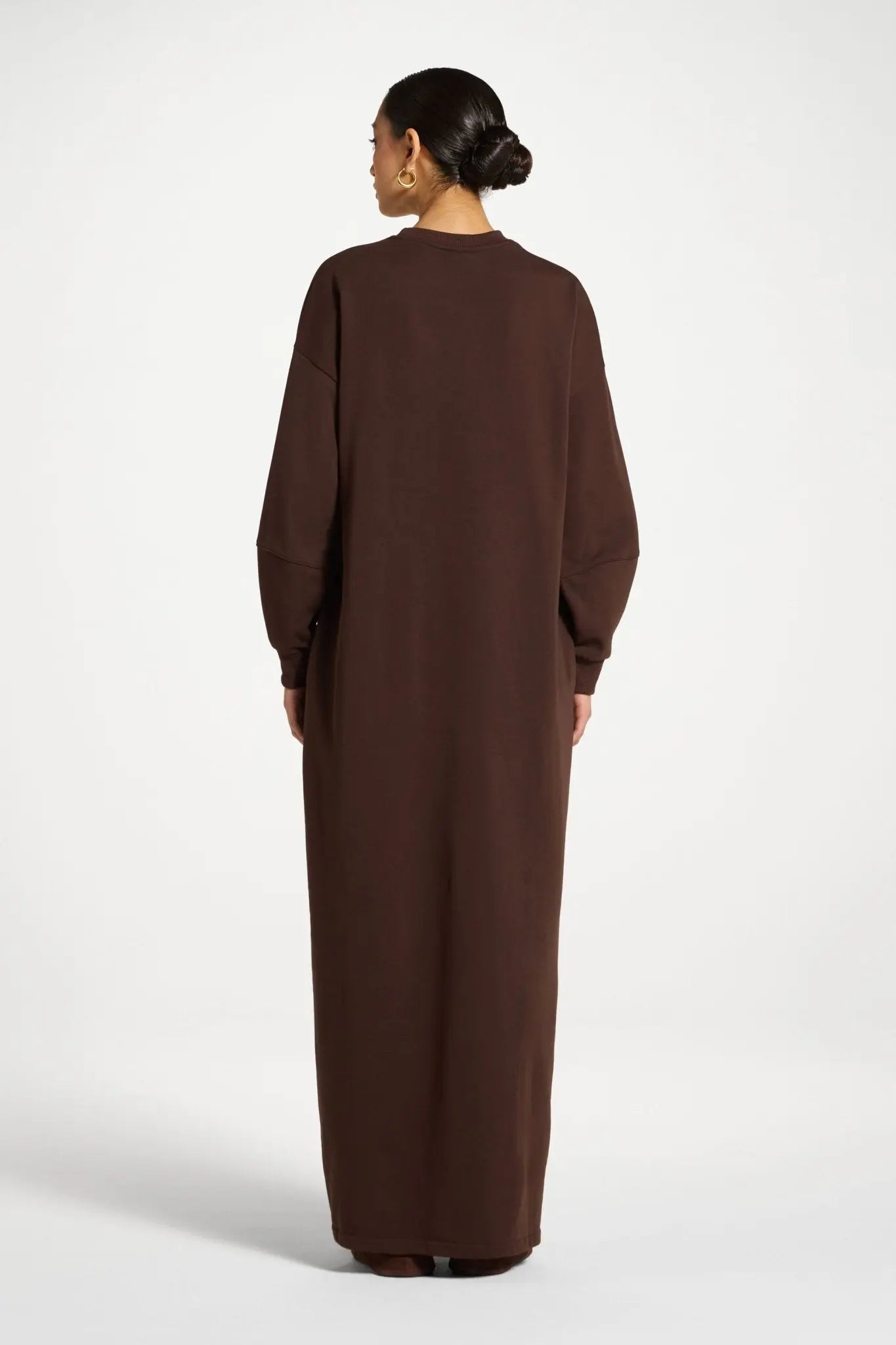 Woman wearing a long brown dress against a white background