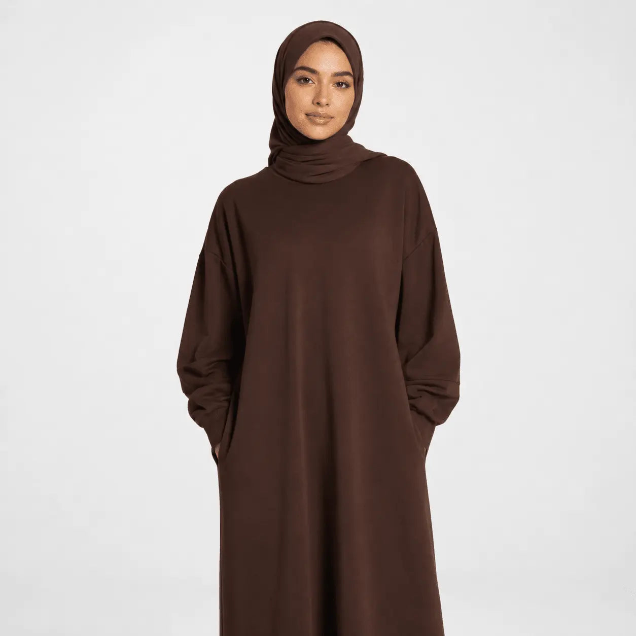 Woman wearing a brown abaya and hijab on a white background