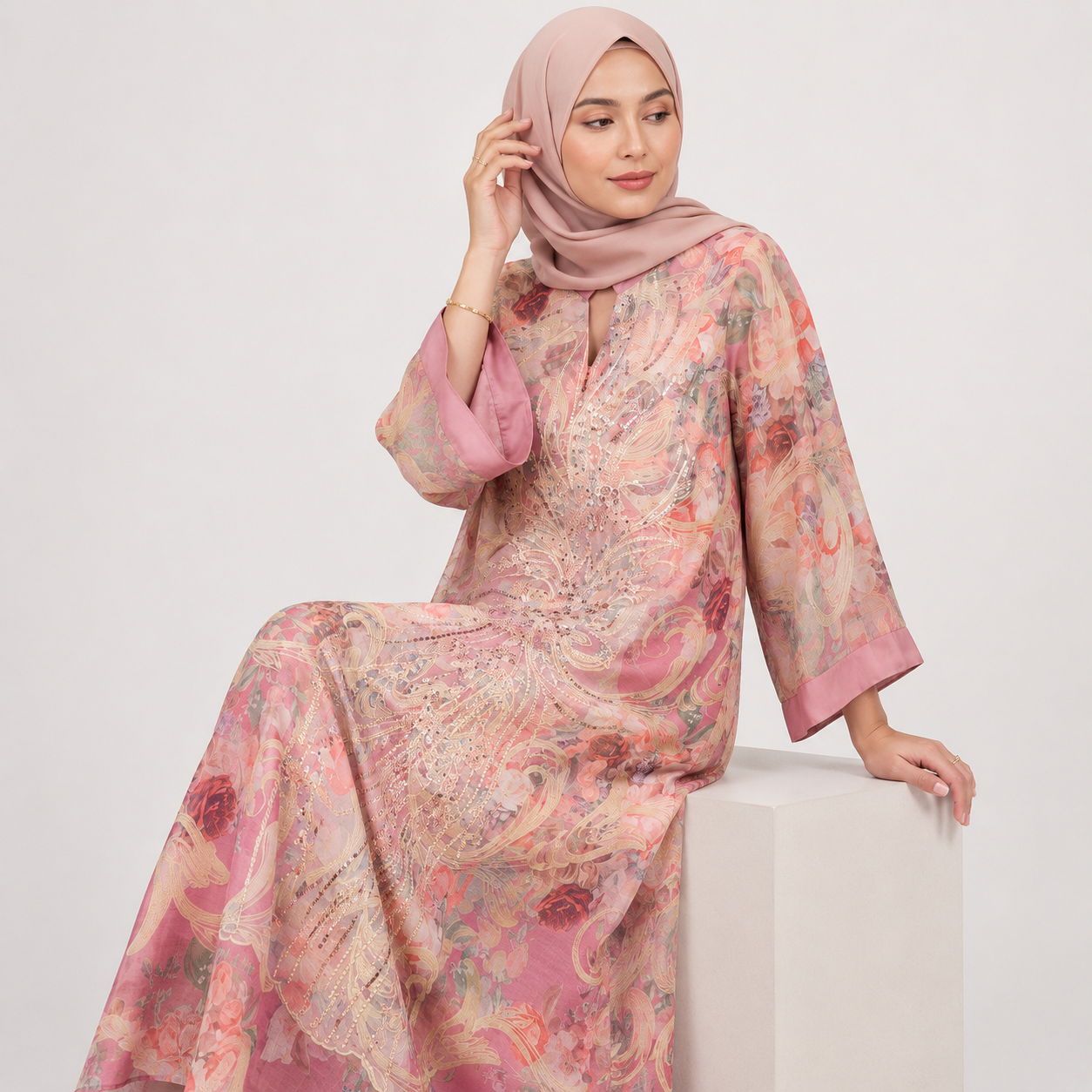 Woman wearing a floral dress with a matching hijab on a white background