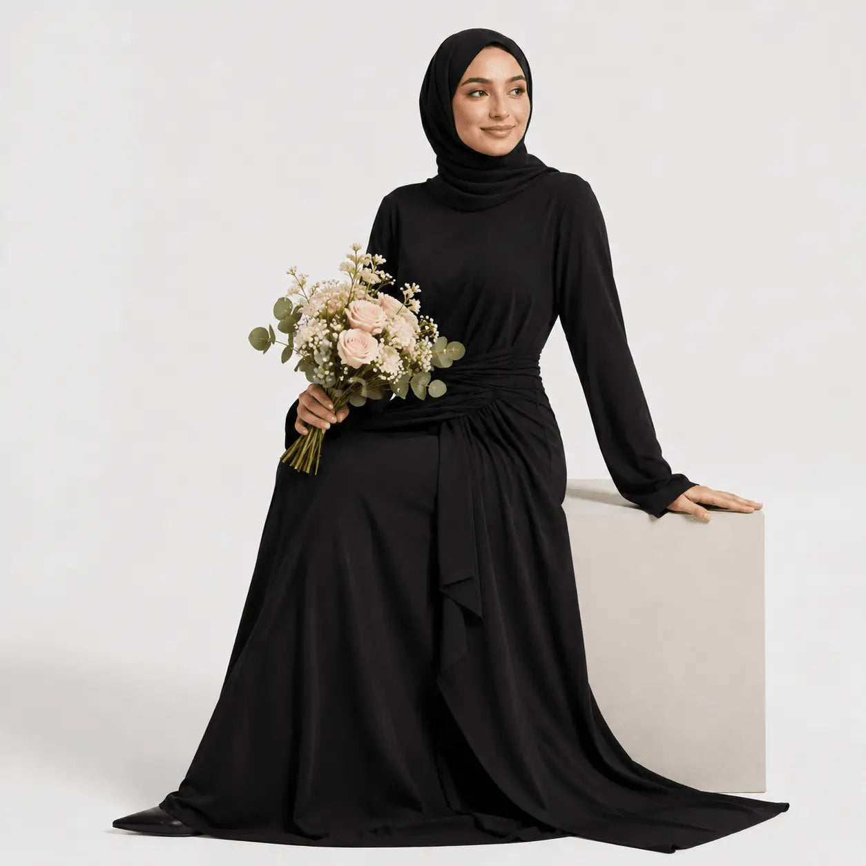 Woman in a black abaya holding flowers against a white background