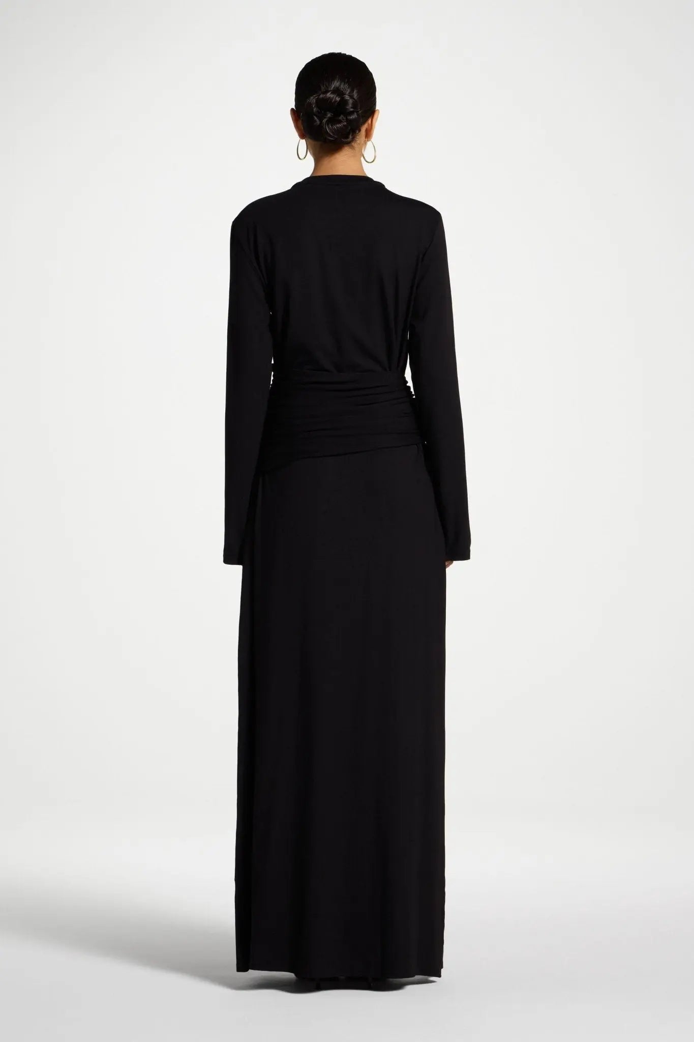 Black long-sleeve dress worn by a person on a white background