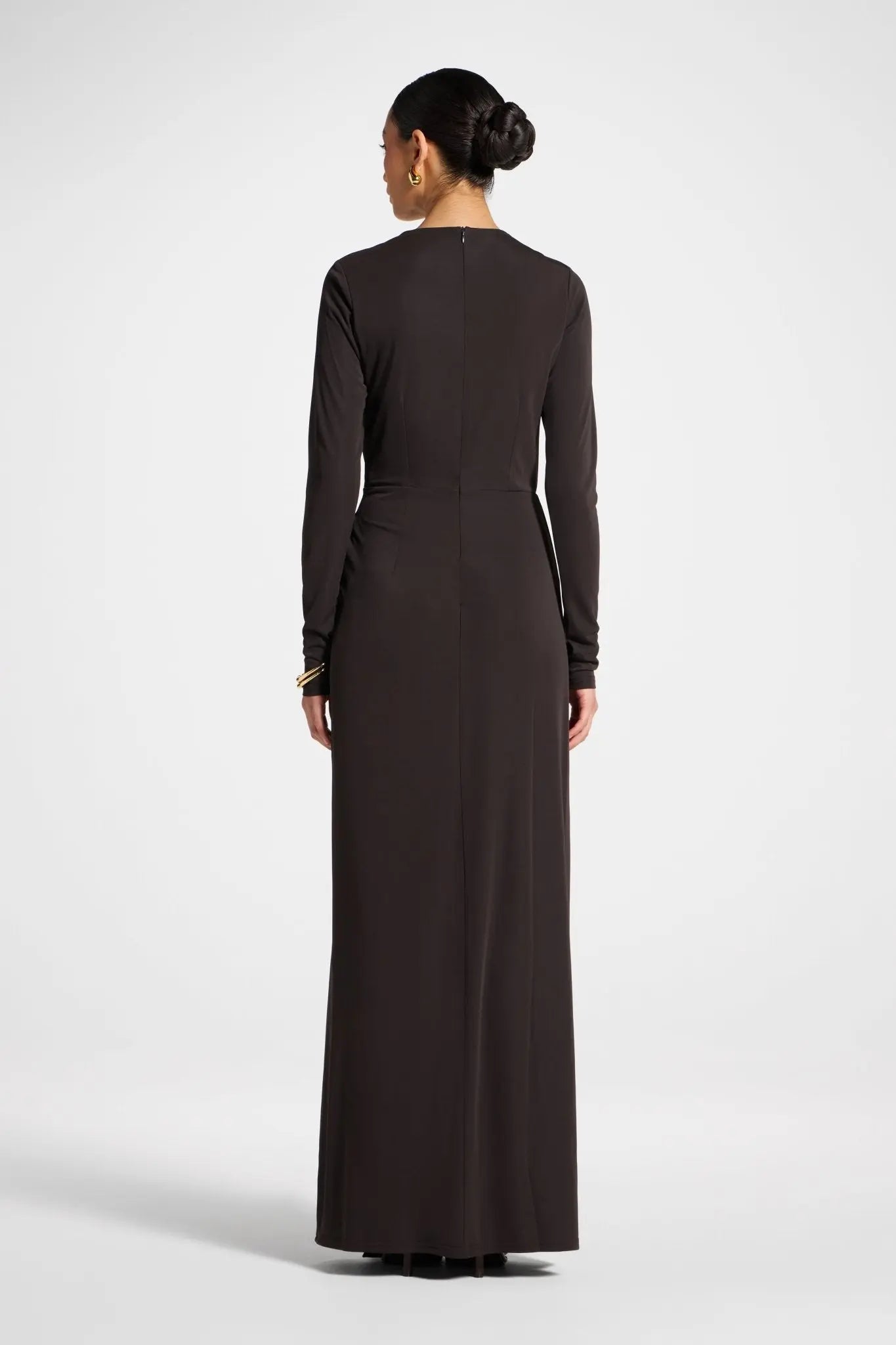 Woman wearing a long dark brown dress on a white background