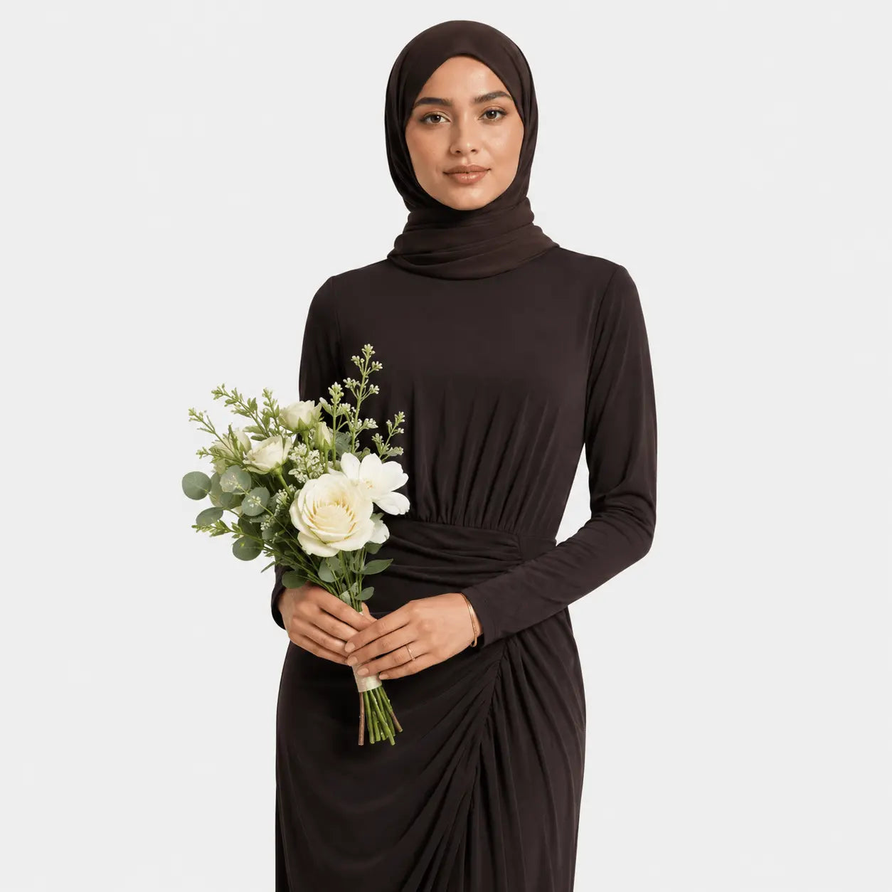 Woman wearing a black hijab and dress holding a bouquet of flowers on a white background