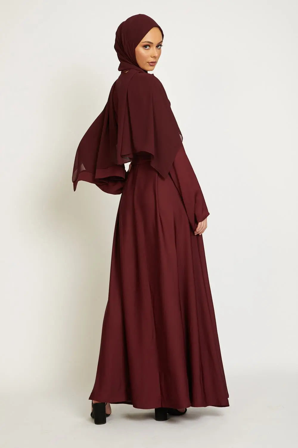 Woman wearing a burgundy dress and hijab on a white background