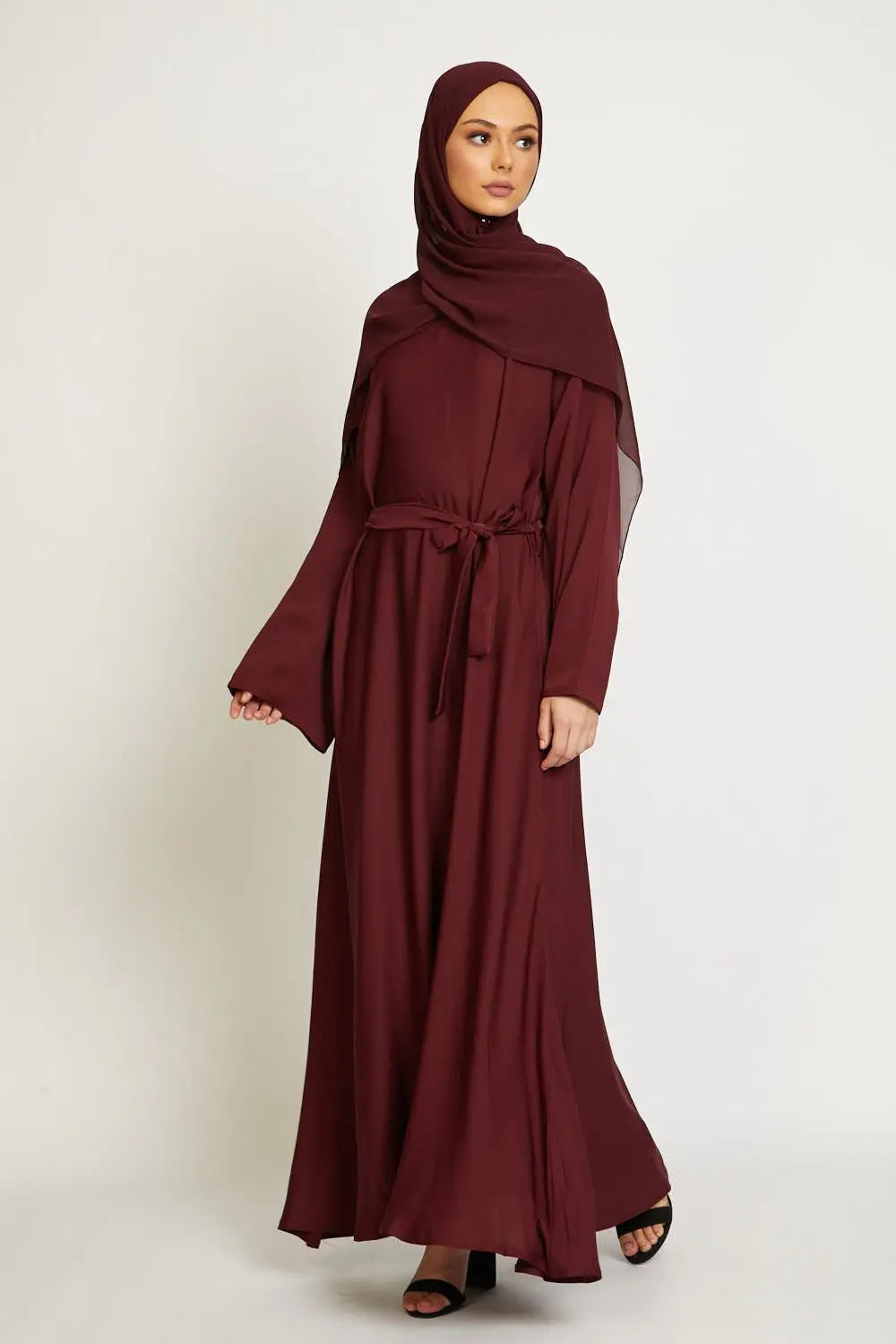Woman wearing a burgundy abaya on a white background
