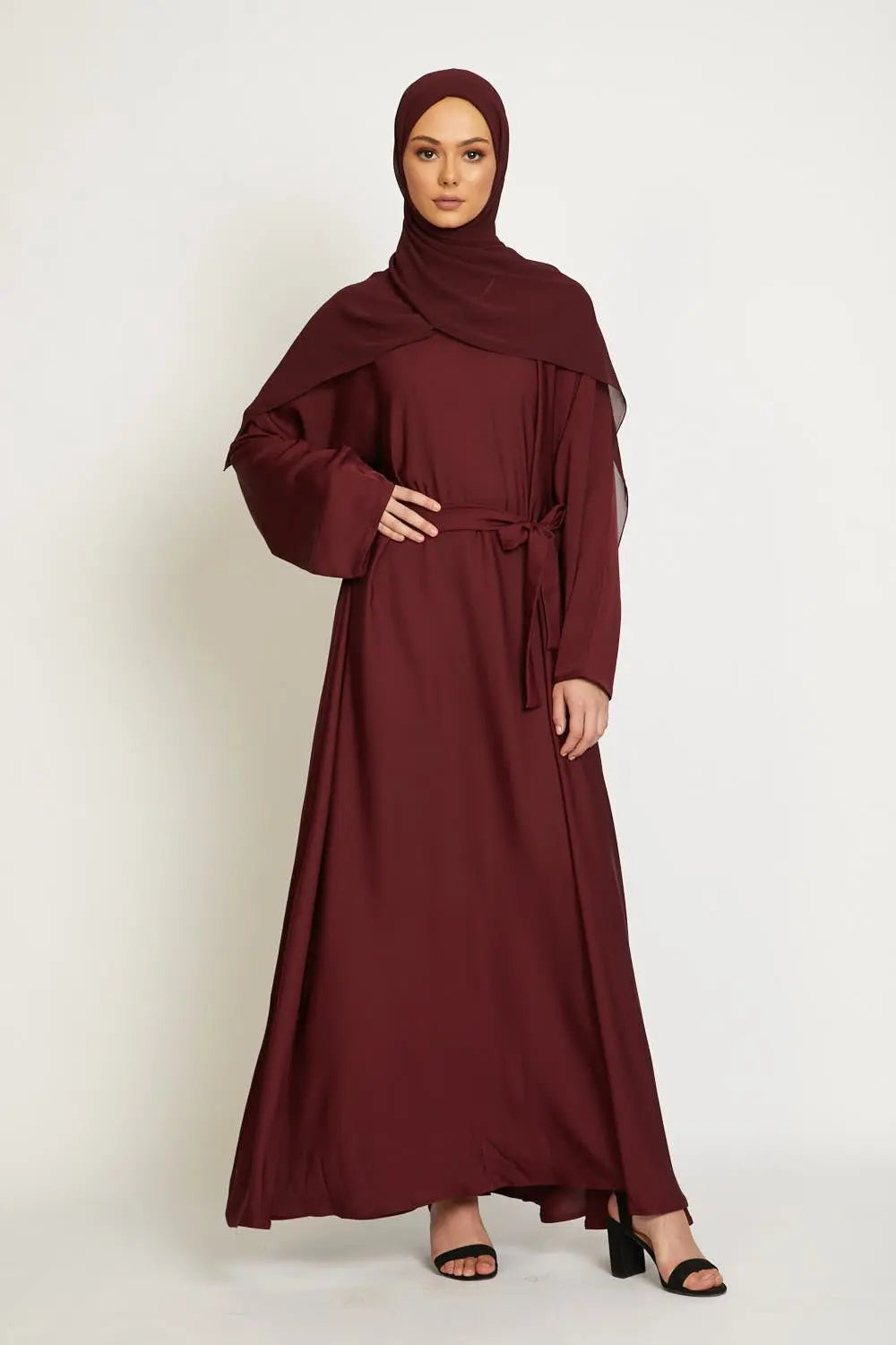 Woman wearing a burgundy dress and hijab on a white background