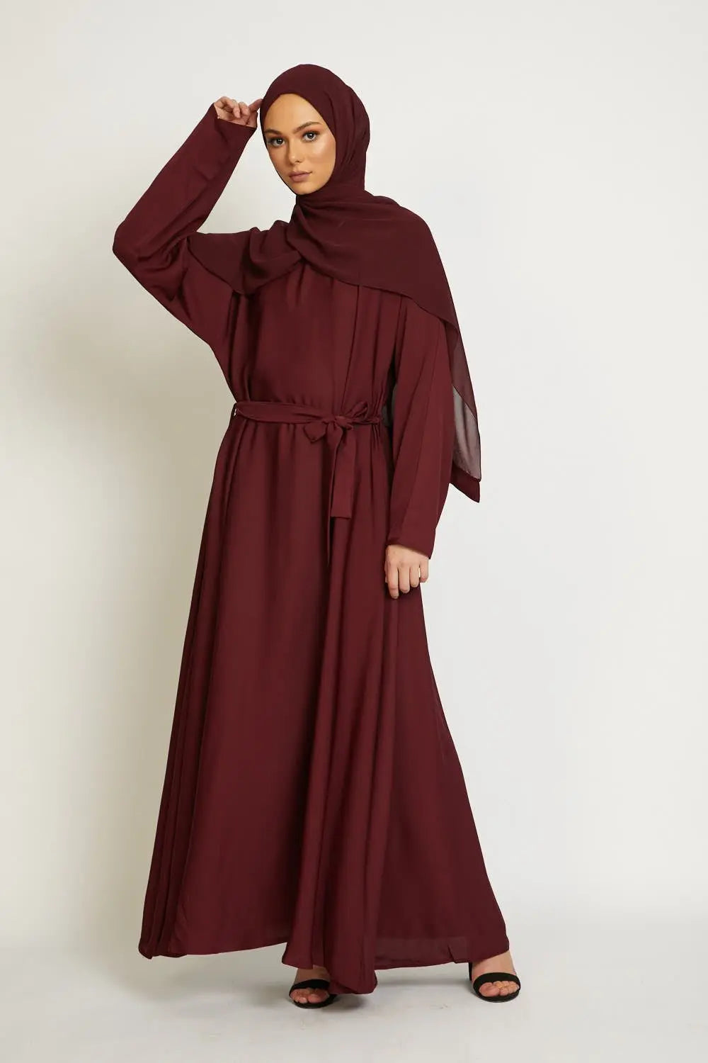 Woman wearing a burgundy abaya on a white background