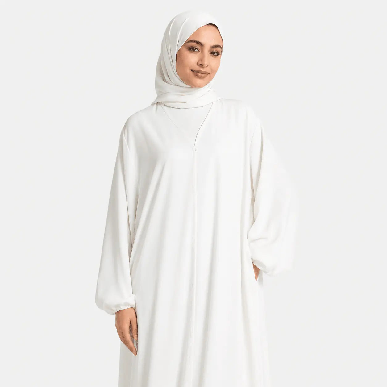 Woman wearing a white abaya and hijab on a white background