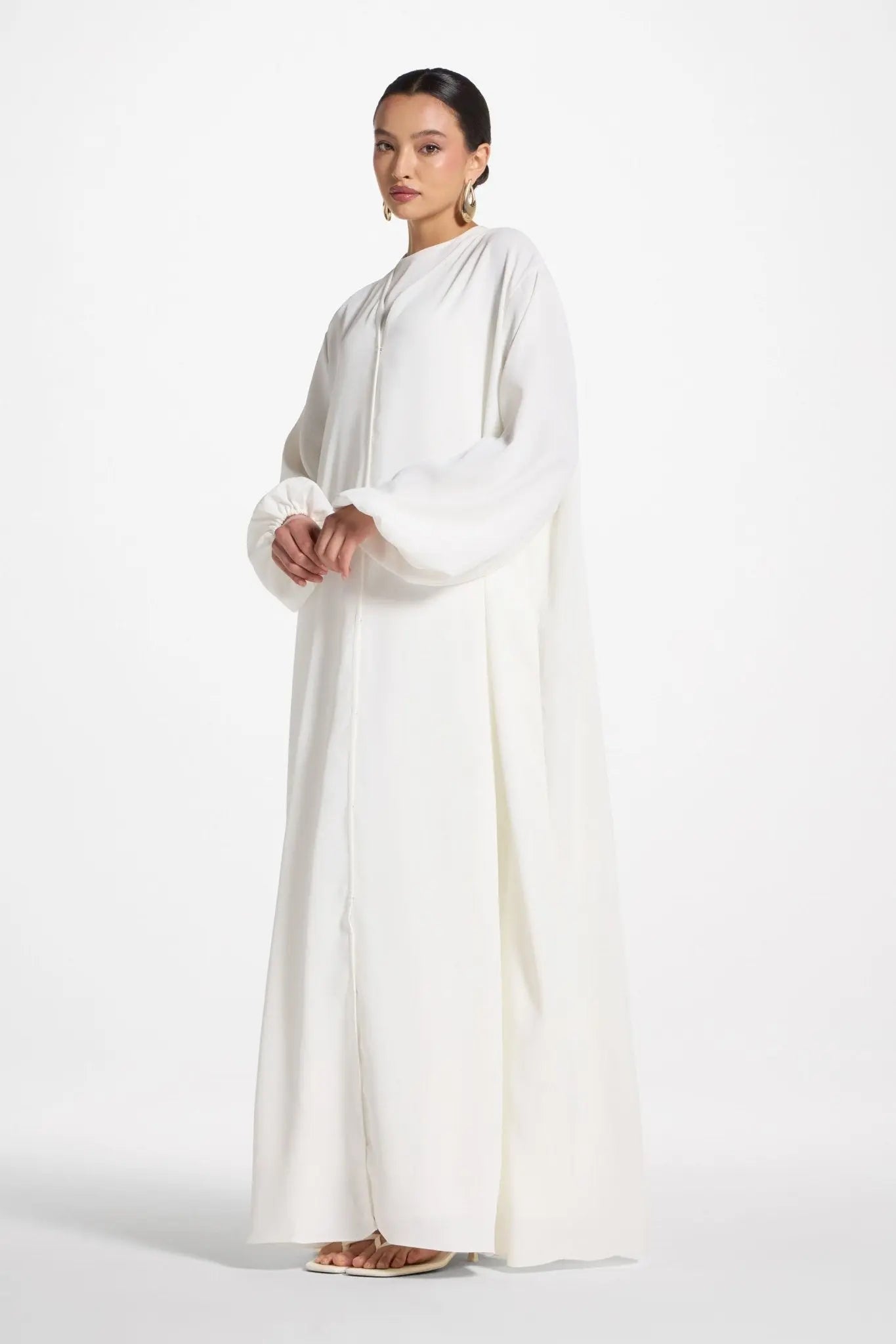 Woman wearing a long white dress on a white background