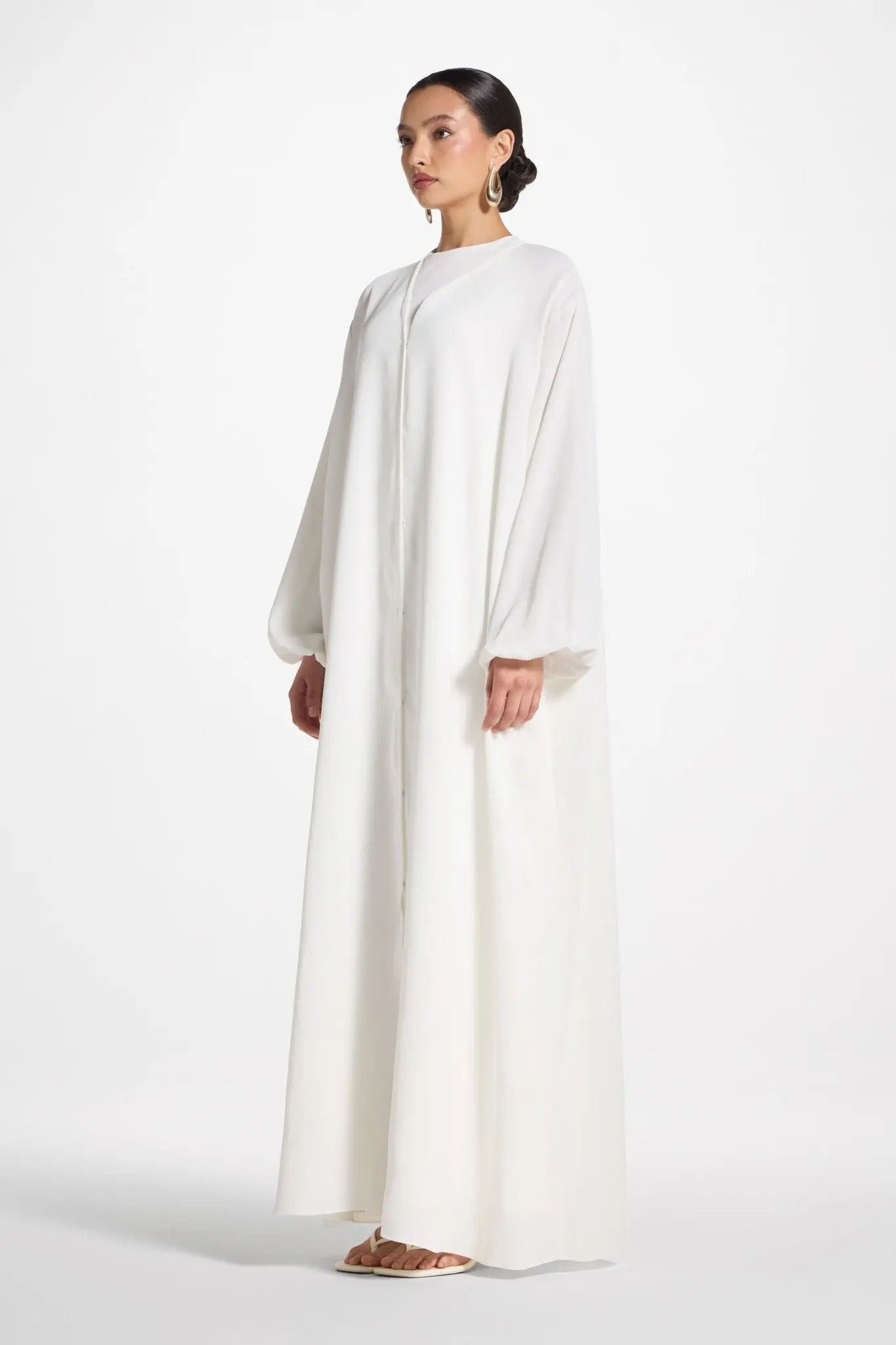 Woman wearing a long white dress on a white background