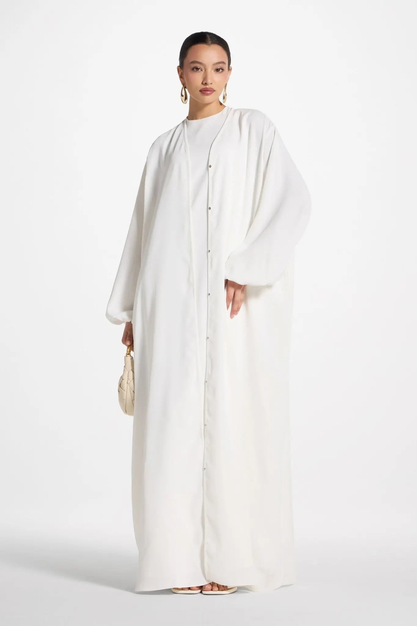 Woman wearing a long white dress against a white background