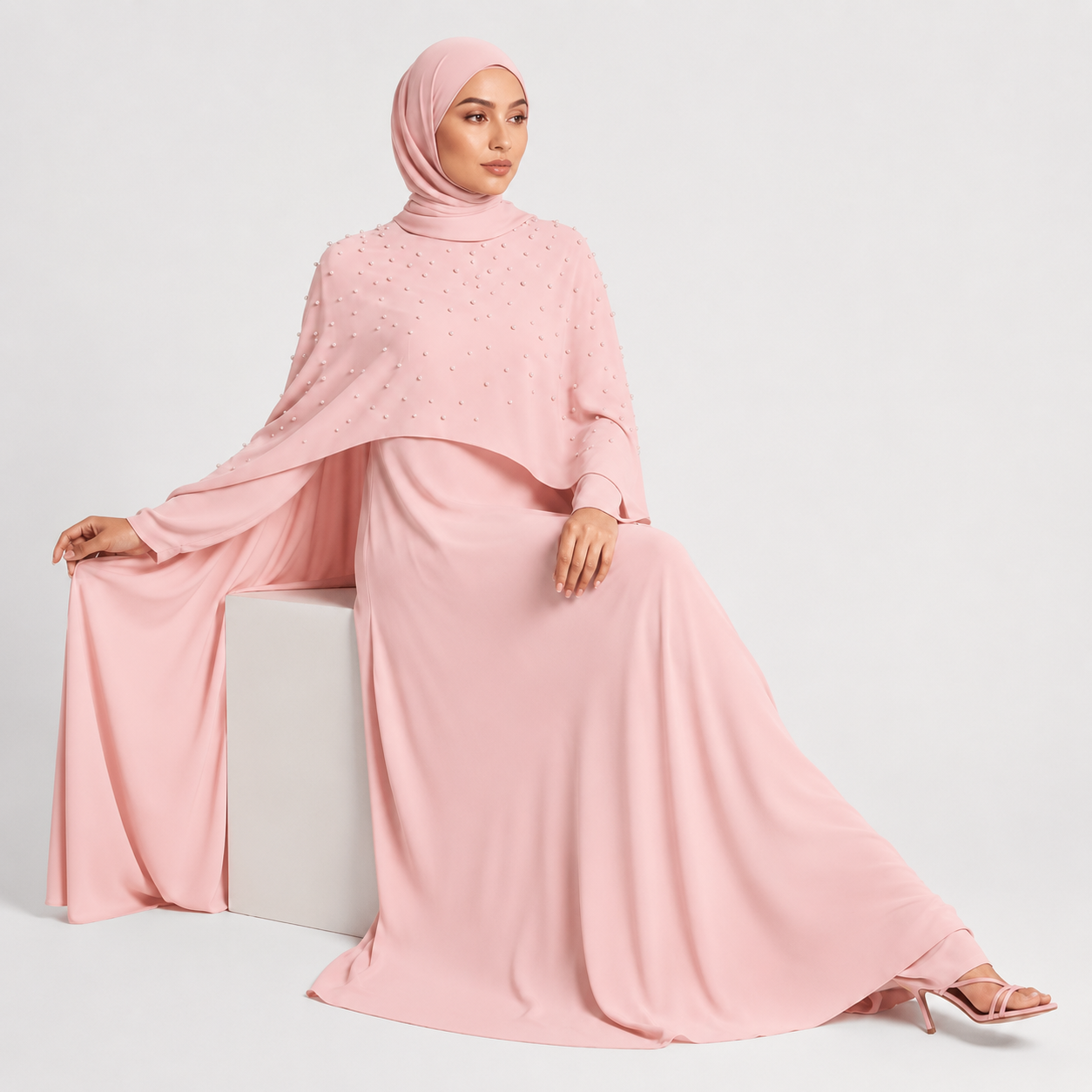 Woman wearing a pink dress and hijab on a white background