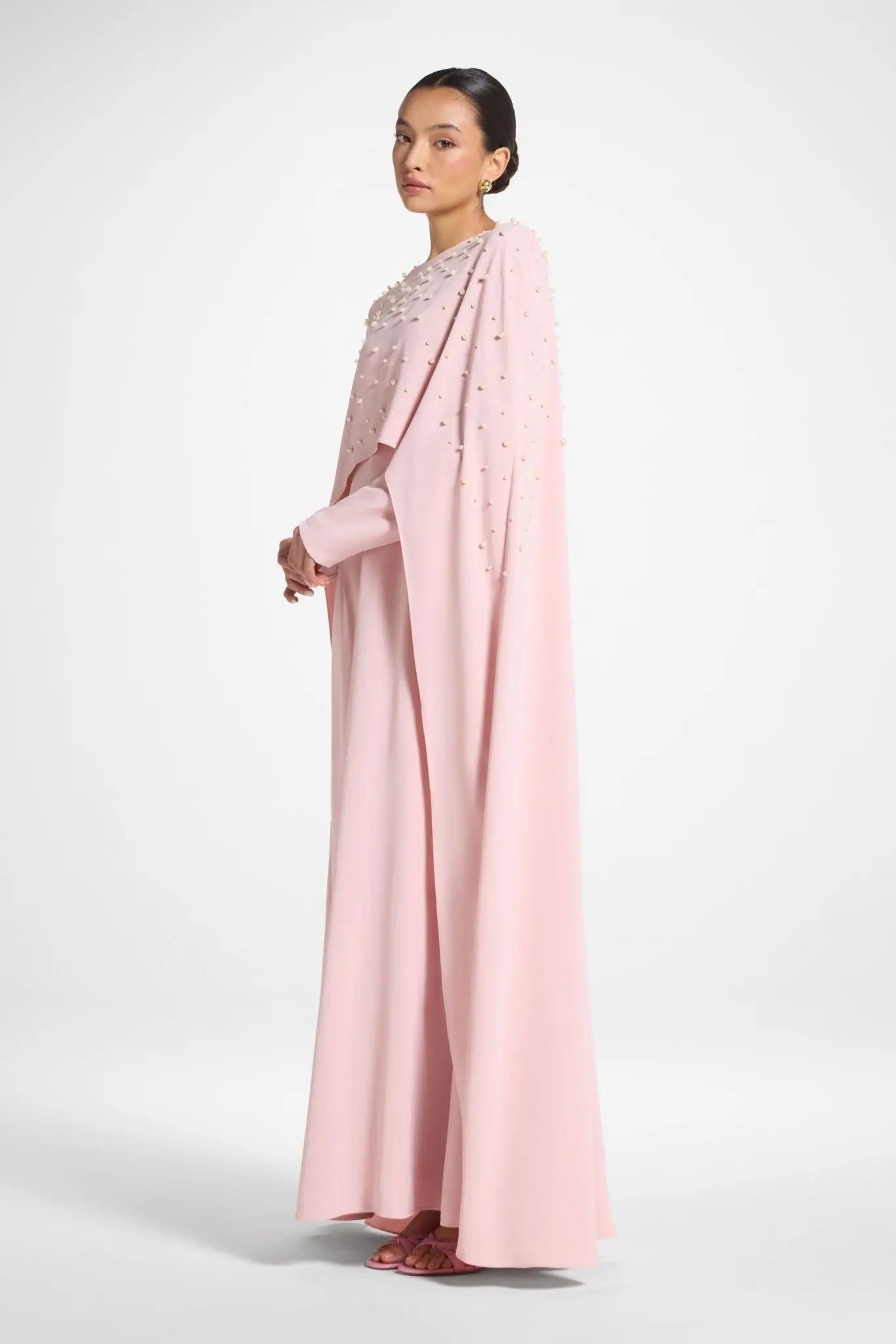 Woman wearing a long light pink dress with a white background