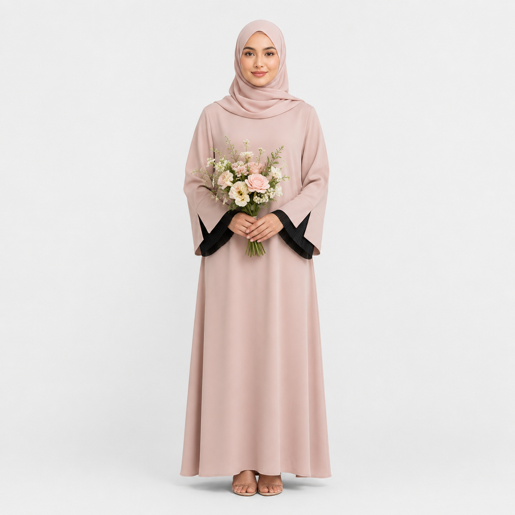 Woman wearing a long light pink dress with black cuffs and holding flowers on a white background