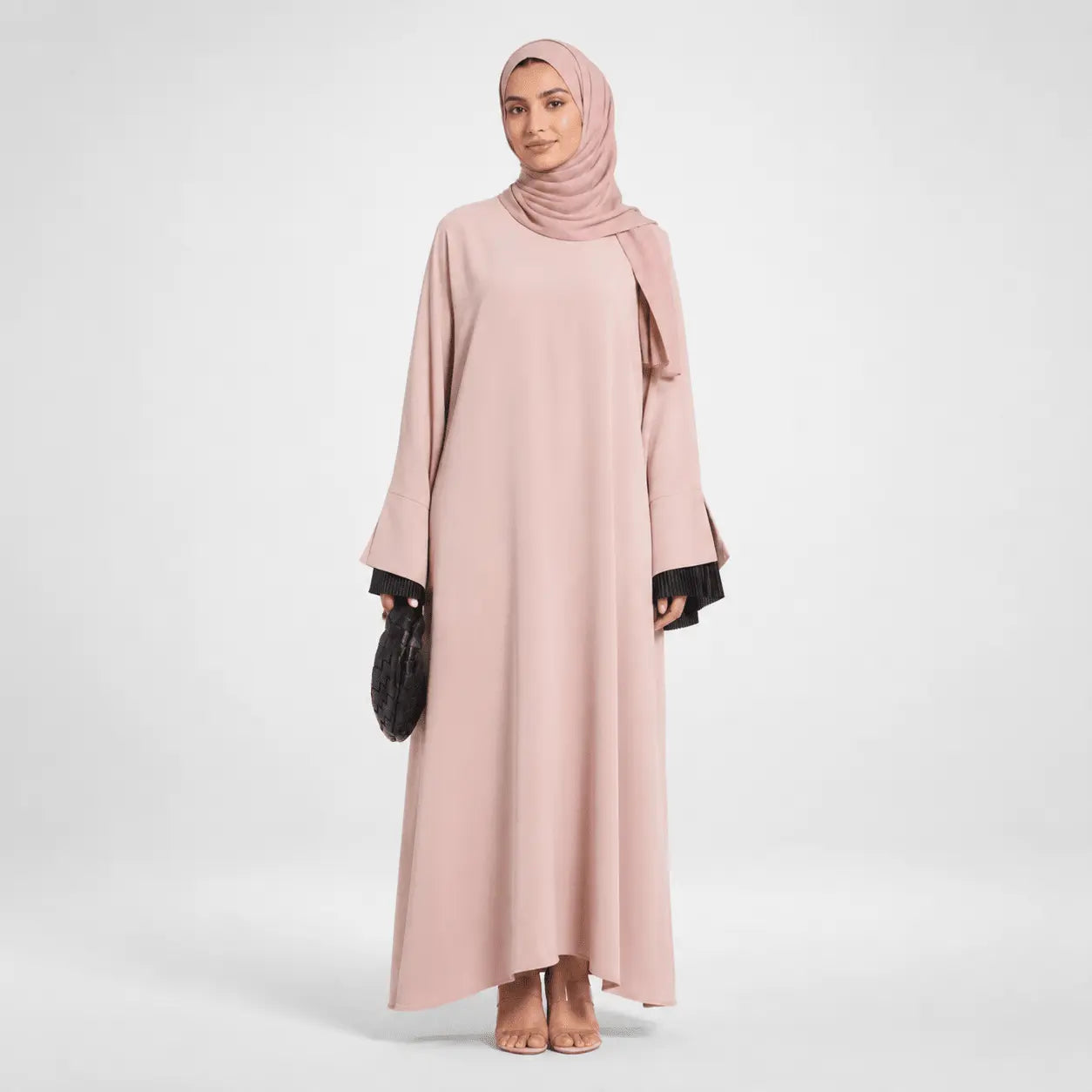 Woman wearing a long pink dress with a matching hijab on a white background