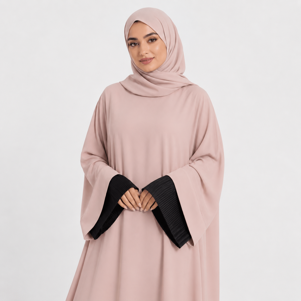 Woman wearing a light pink abaya with black sleeves on a white background
