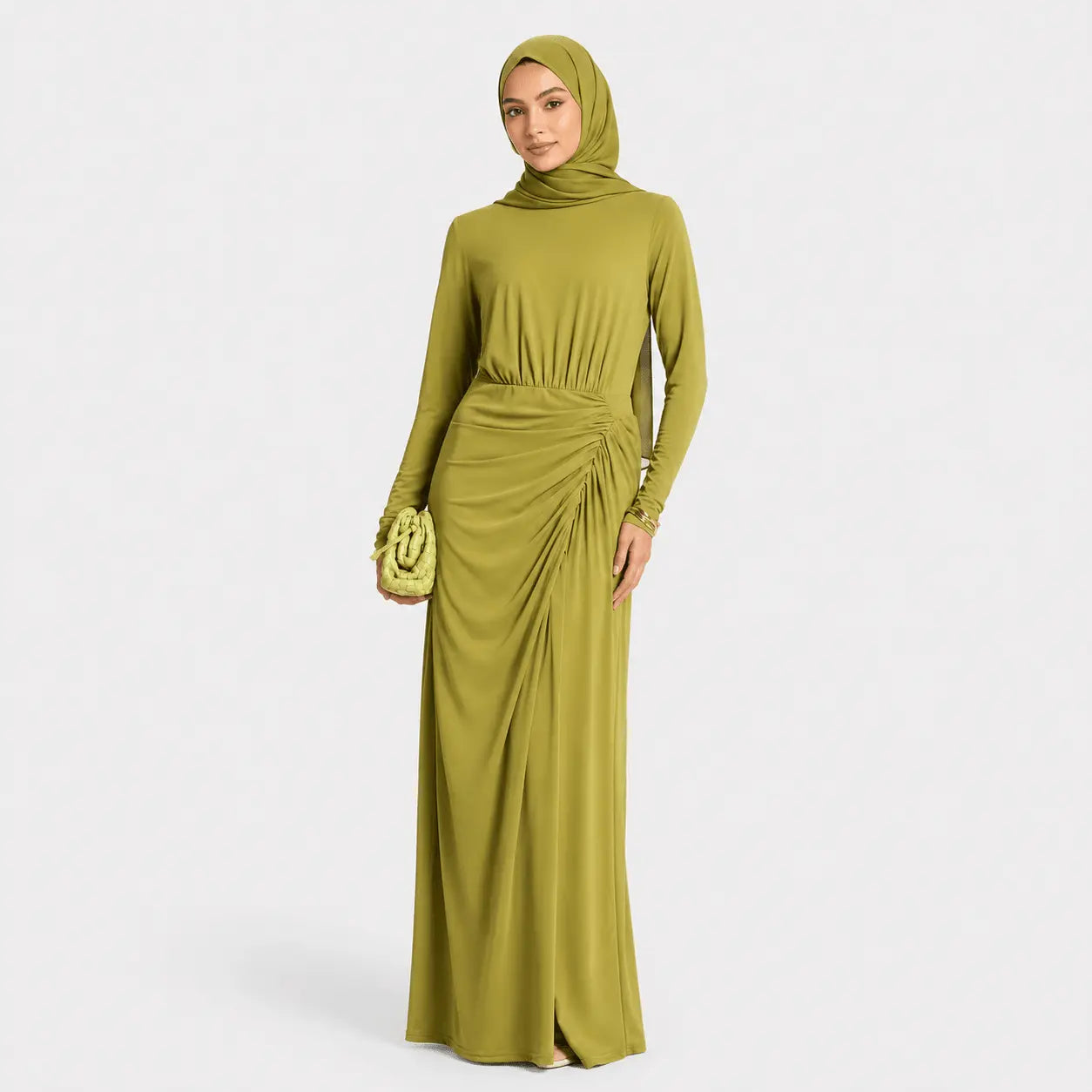 Woman wearing a green long-sleeve dress with a matching hijab on a white background