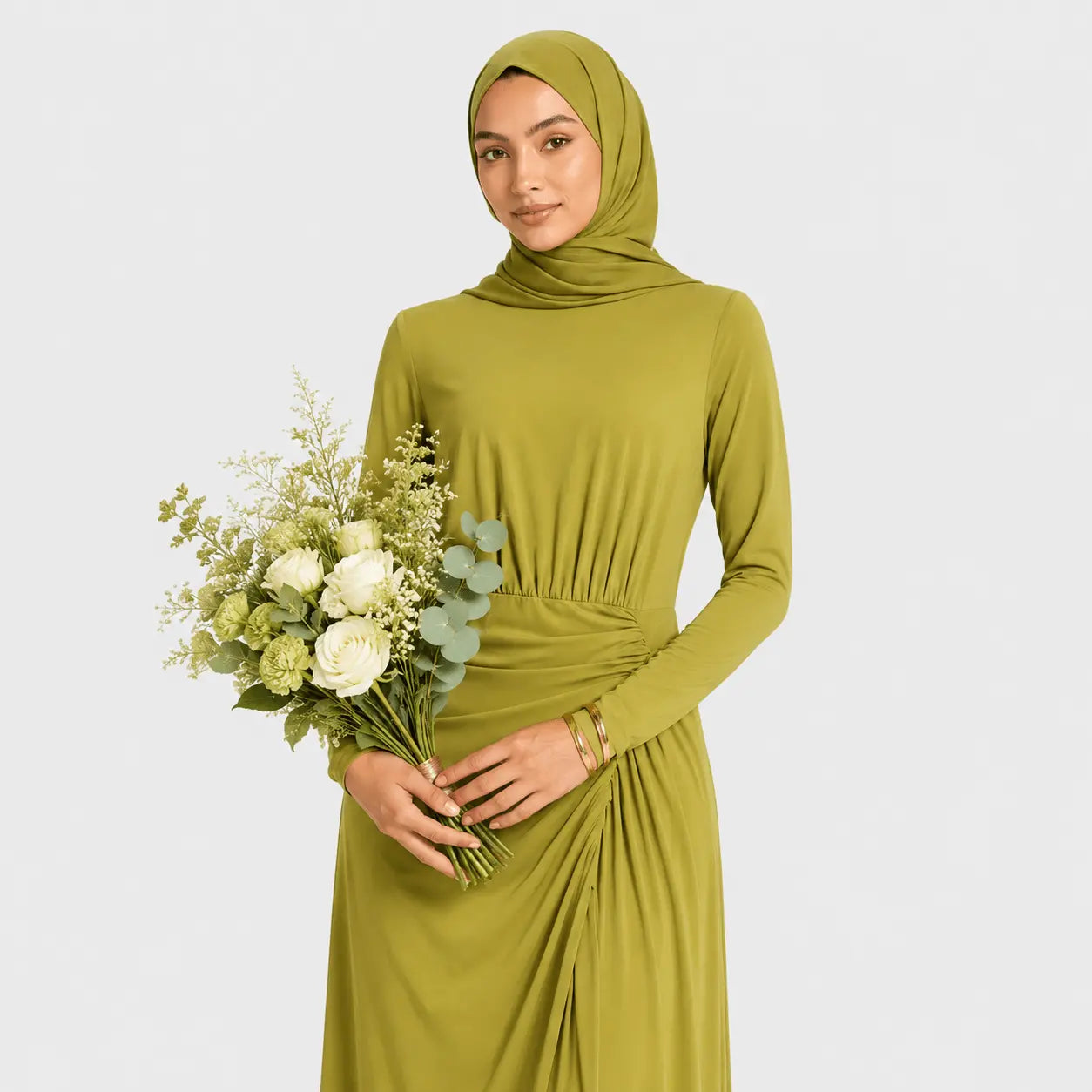 Woman wearing a green dress and hijab holding flowers on a light gray background