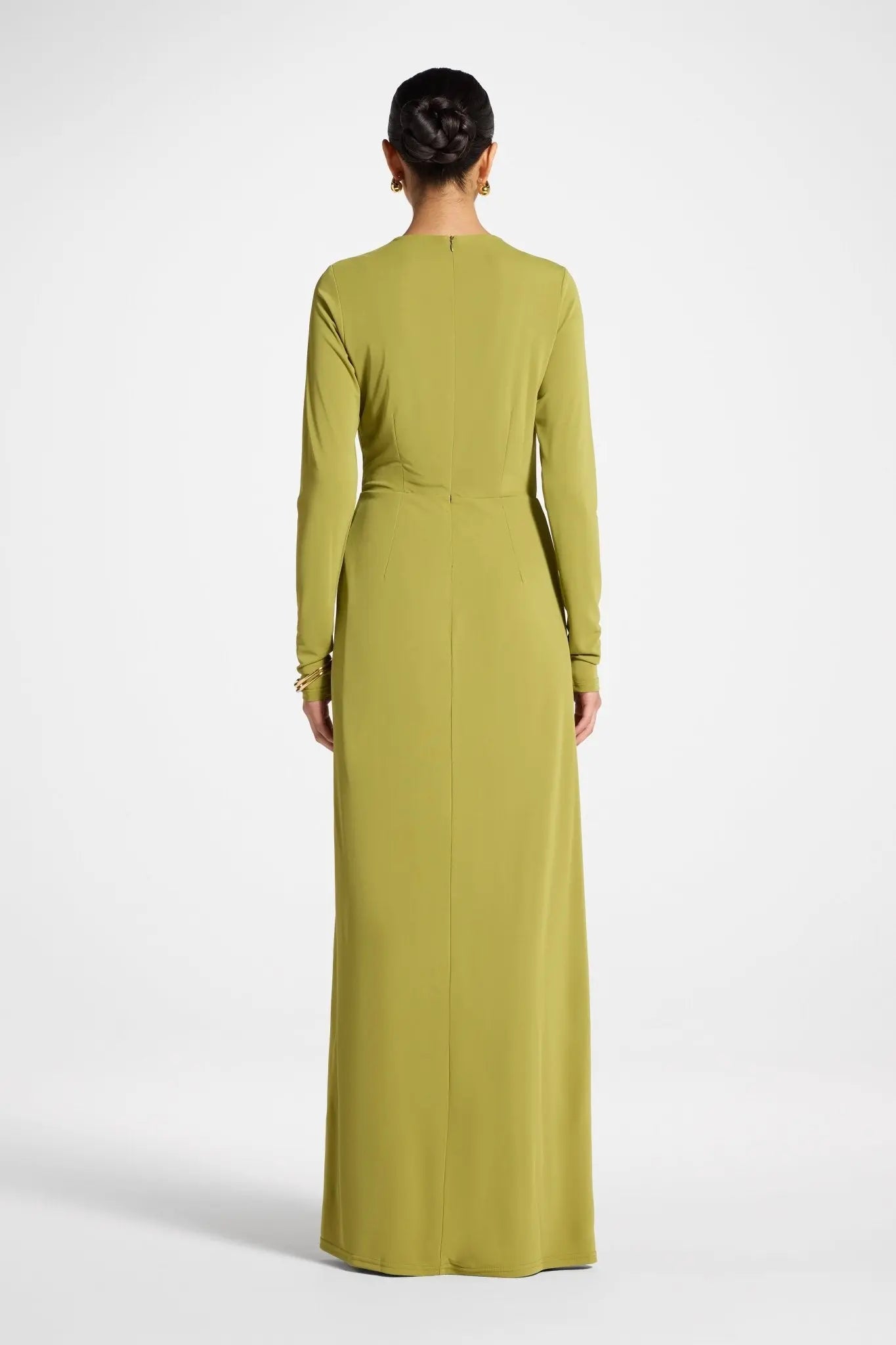 Woman wearing a long green dress on a white background