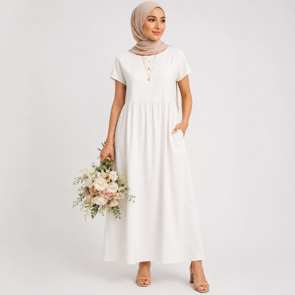 Woman in a white dress holding flowers against a plain background