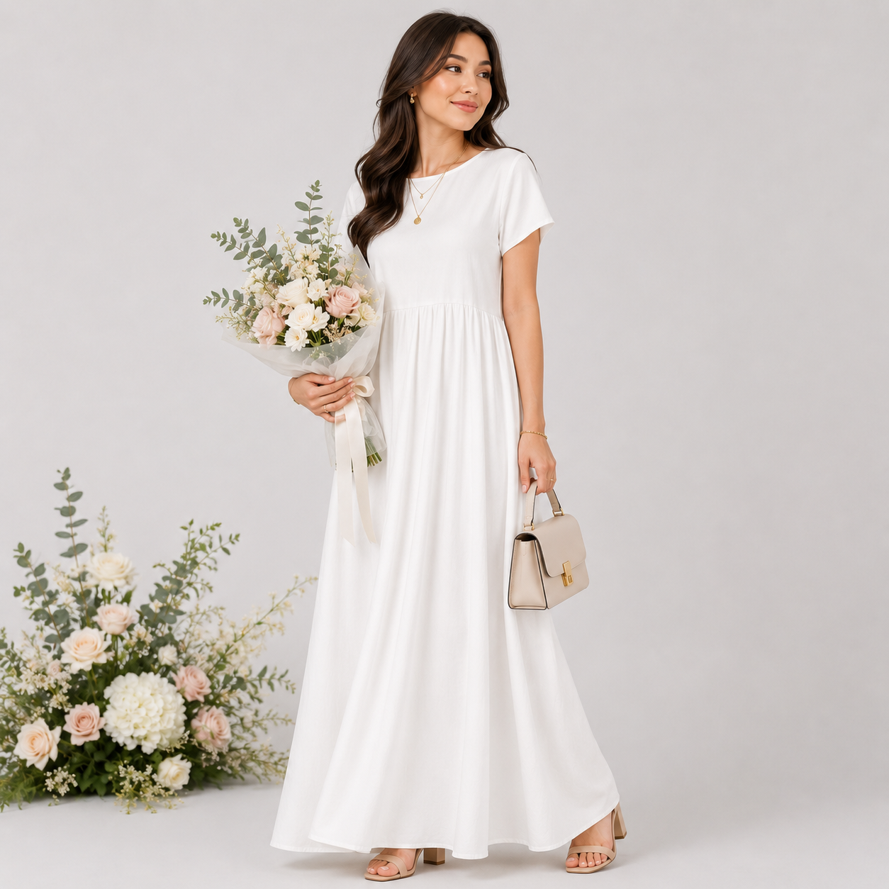 Woman in a white dress holding flowers and a handbag on a light gray background