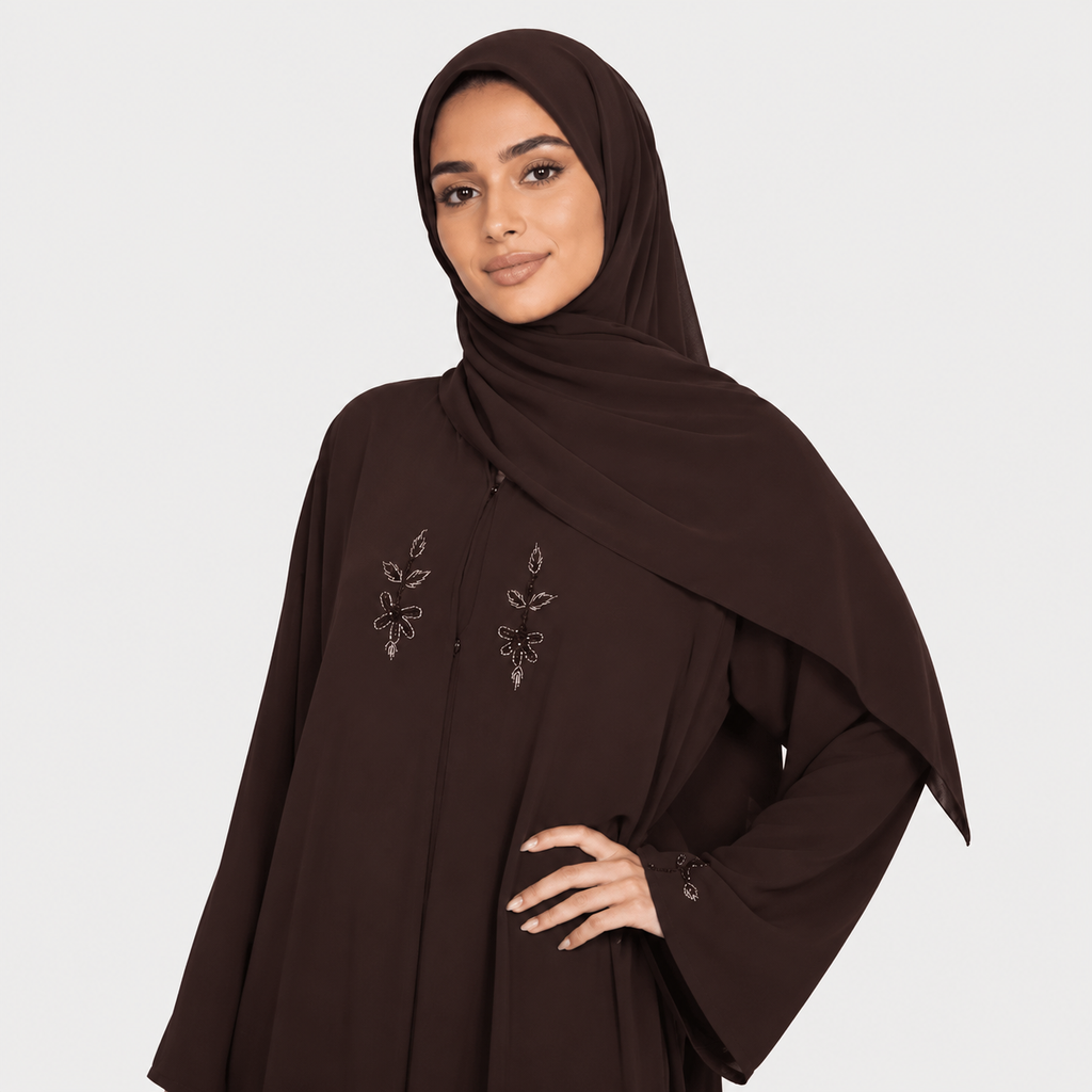 Woman wearing a brown abaya with floral embroidery on a white background
