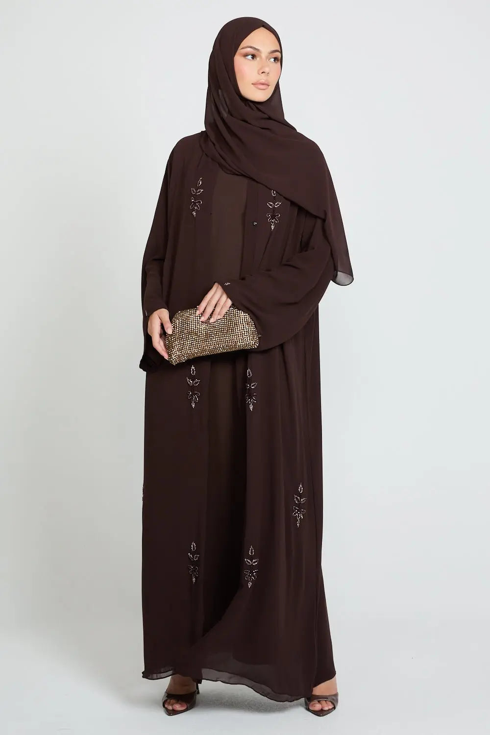 Woman wearing a brown abaya with intricate designs on a white background