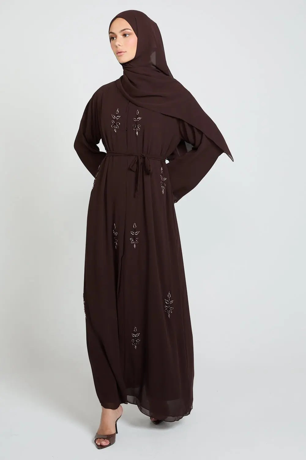 Woman wearing a brown abaya with embroidery on a white background