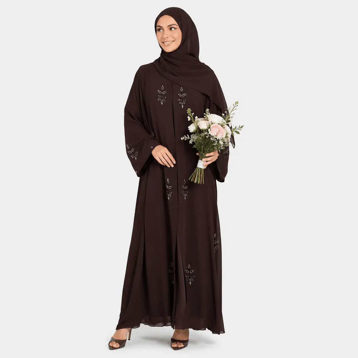 Woman wearing a dark brown abaya holding flowers on a light gray background