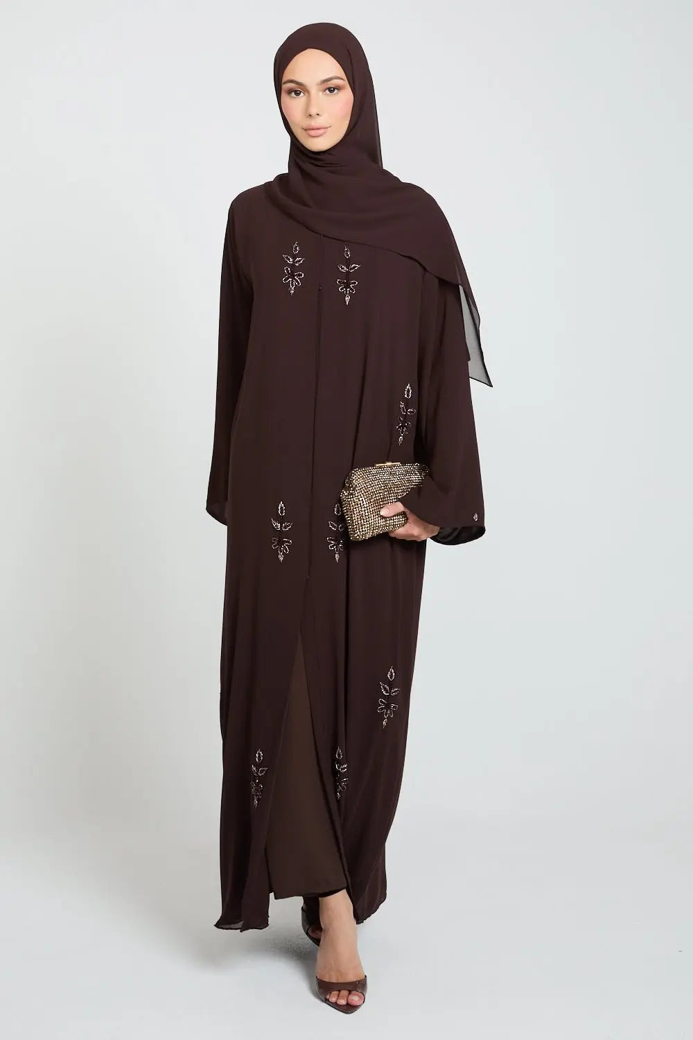 Woman wearing a brown abaya with intricate designs on a white background