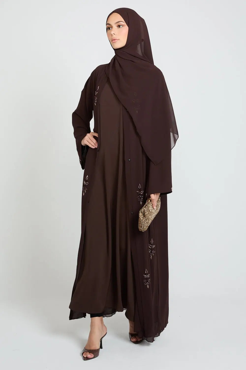 Woman wearing a brown abaya with a matching hijab on a white background