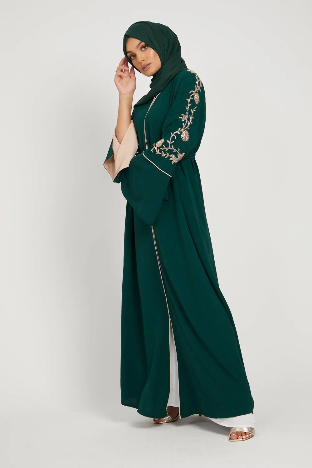 Woman wearing a green abaya with embroidery on a white background