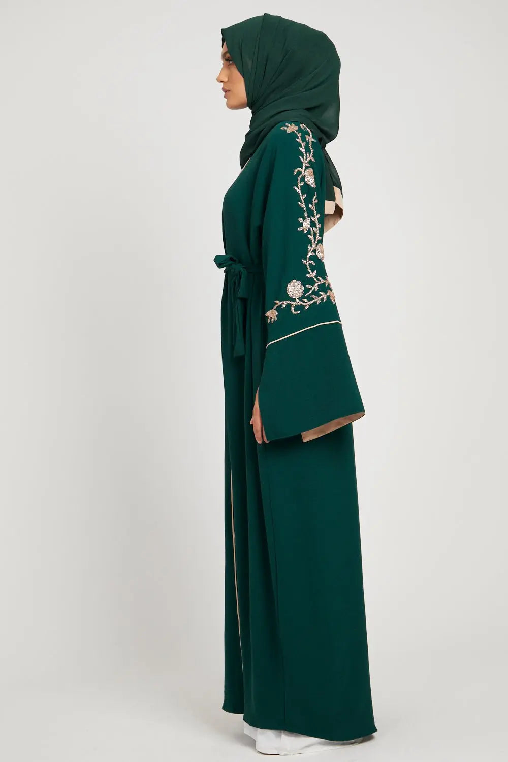 Green embroidered abaya worn by a model on a white background