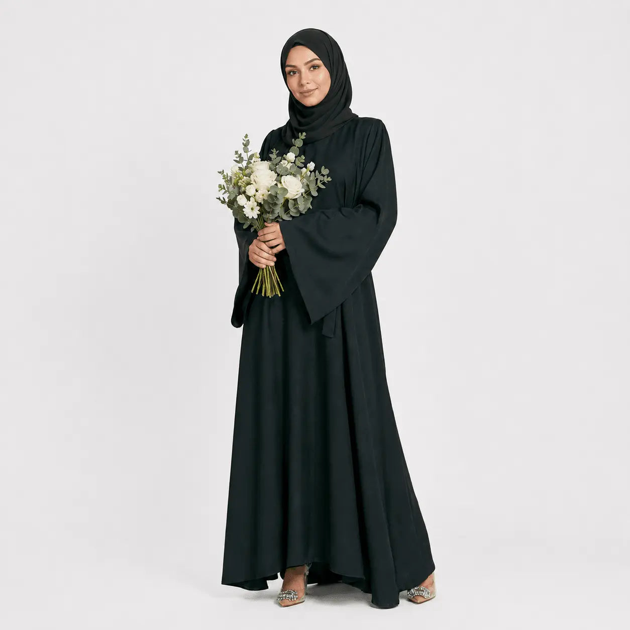Woman in a black abaya holding flowers on a white background