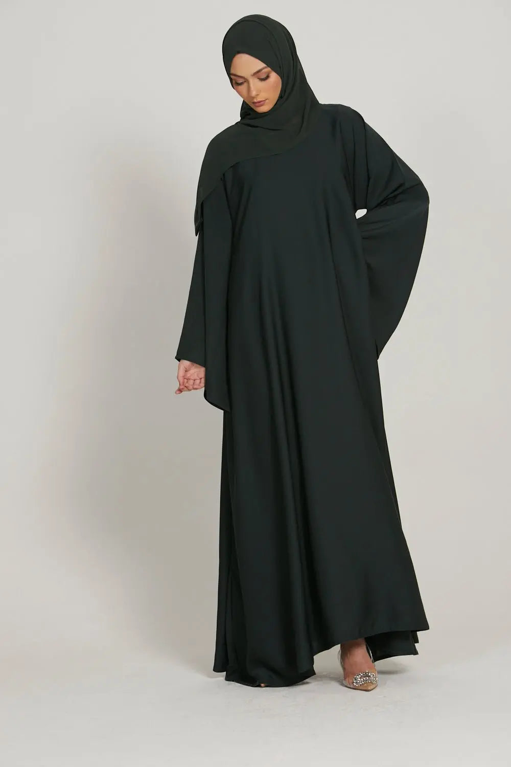 Person wearing a black abaya on a plain background