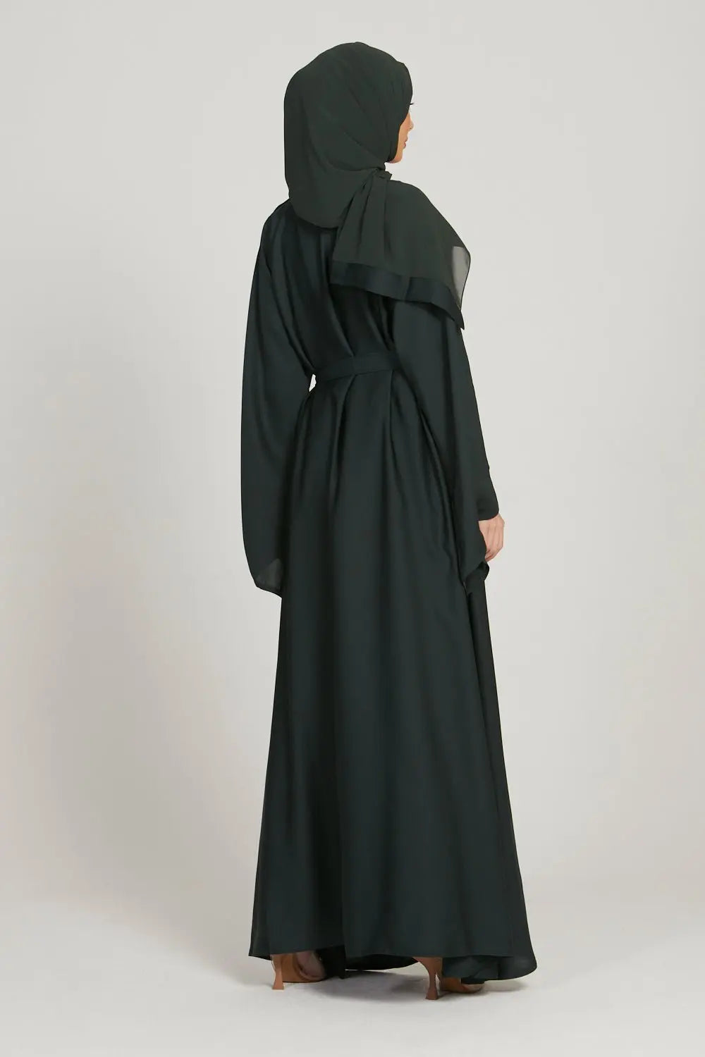 Person wearing a dark green abaya on a white background
