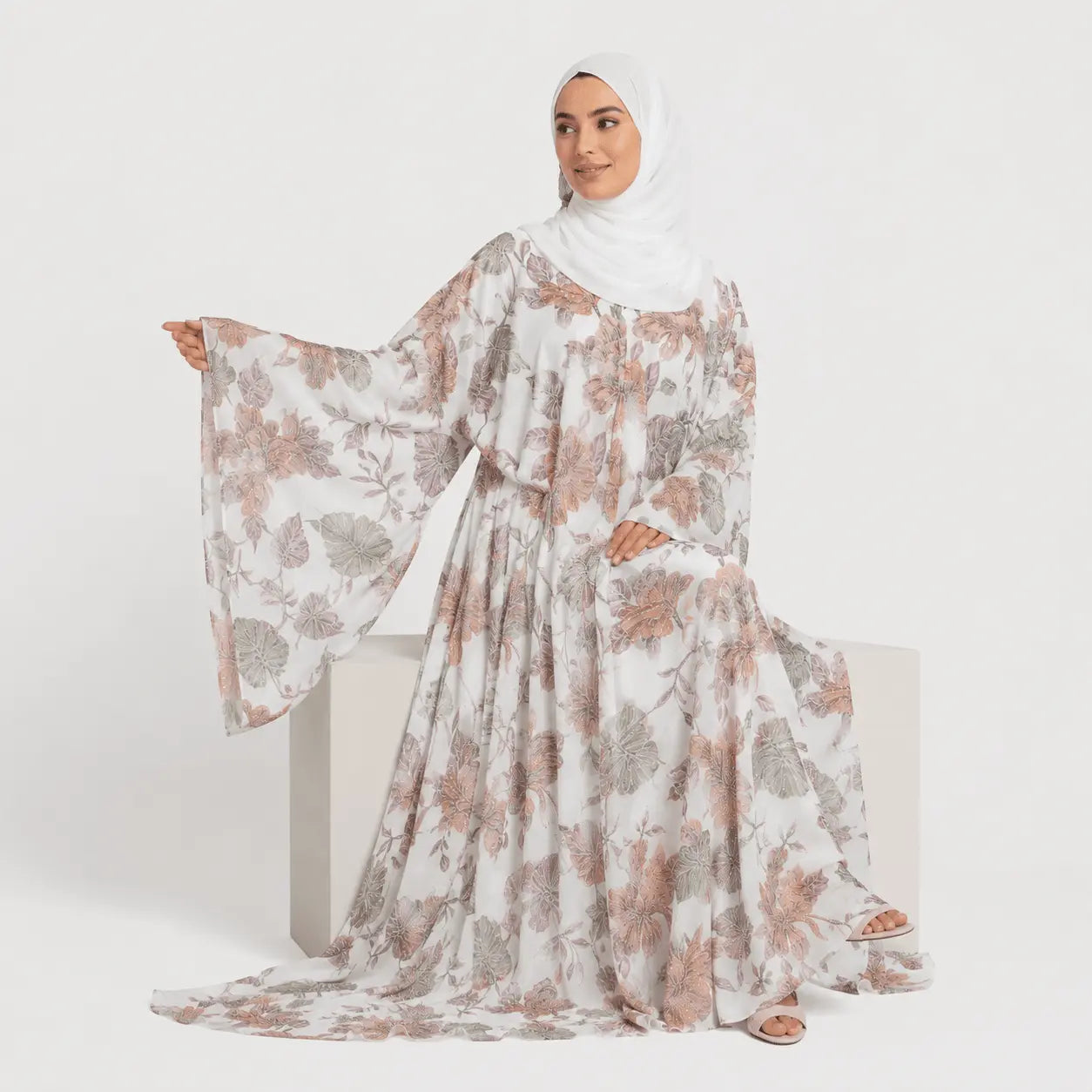 Woman wearing a floral dress with a hijab on a white background