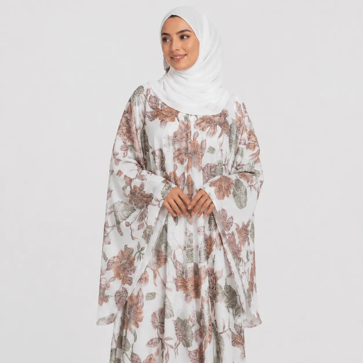 Woman wearing a floral dress with a white hijab on a light gray background