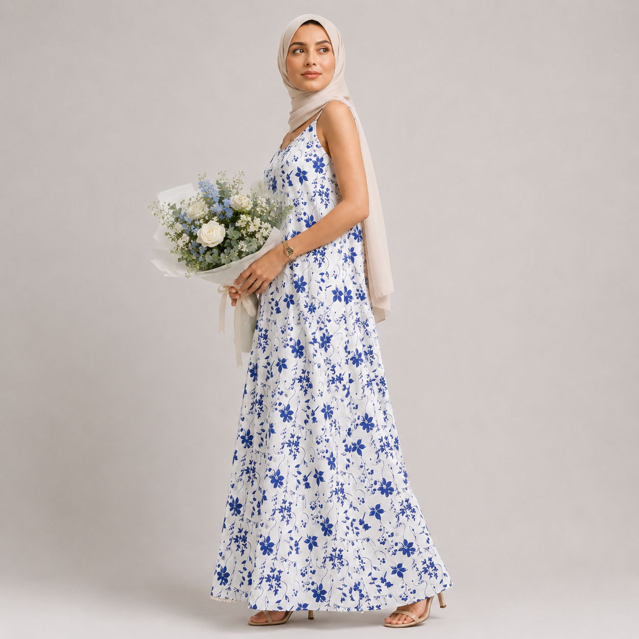 Woman in a floral dress holding flowers against a plain background