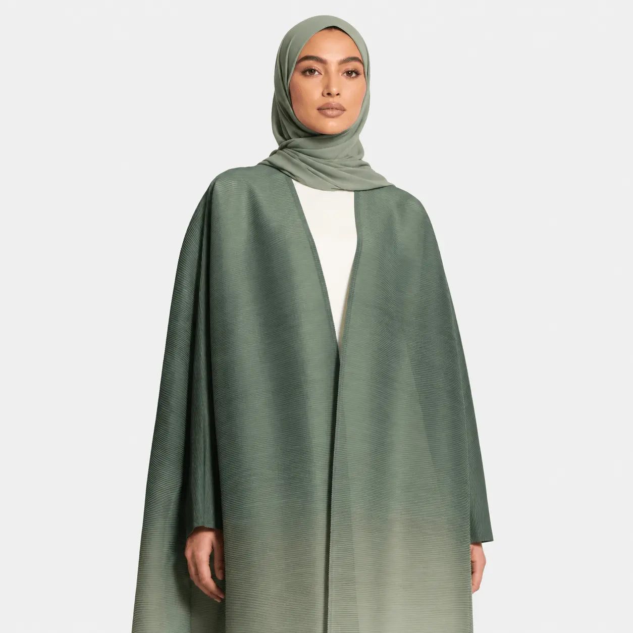 Woman wearing a green abaya and hijab on a white background