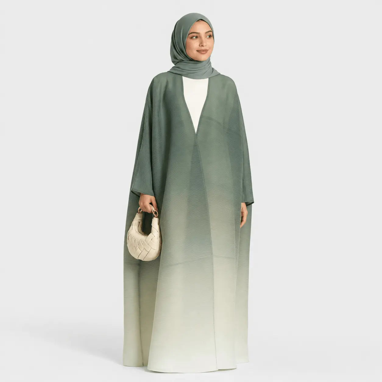 Woman wearing a green gradient abaya with a white top on a light gray background