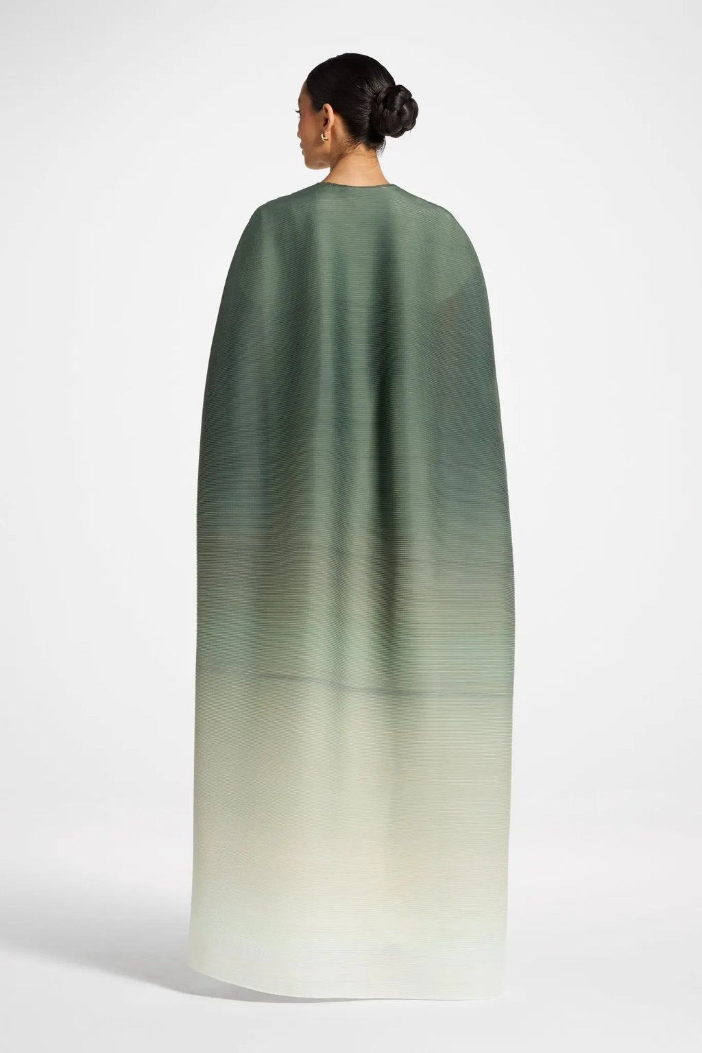 Woman wearing a green to beige gradient cape on a white background