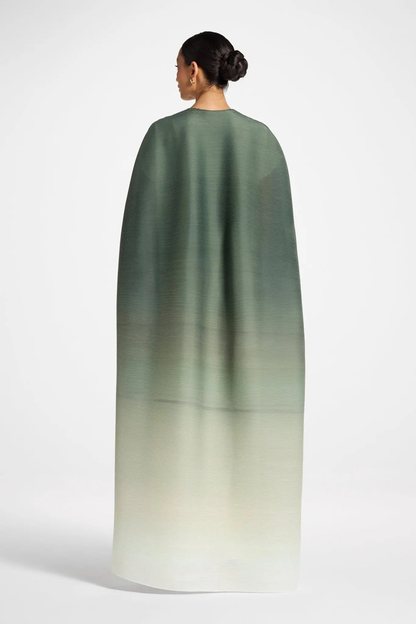 Woman wearing a green to beige gradient cape on a white background