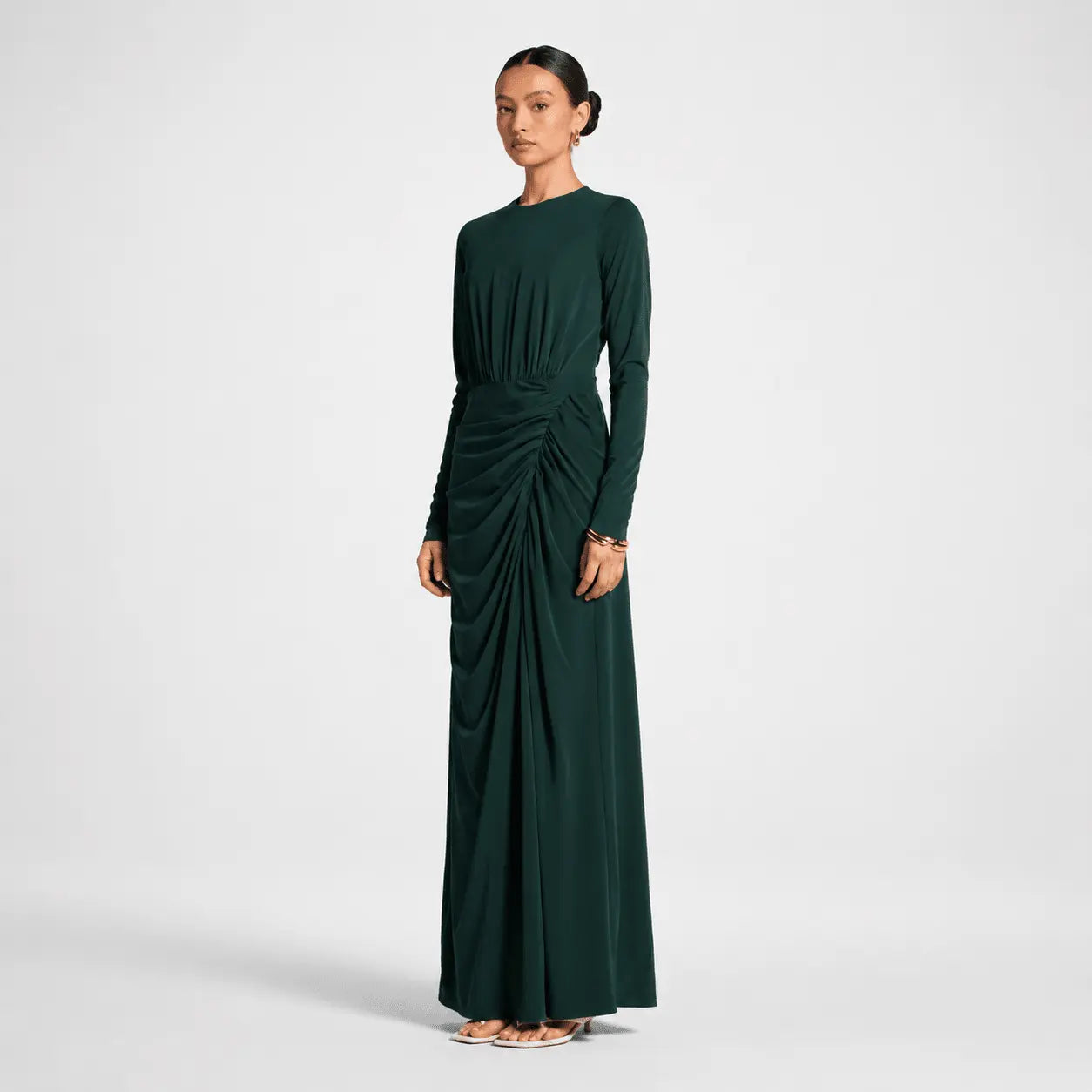 Woman wearing a dark green dress with a draped effect on a white background