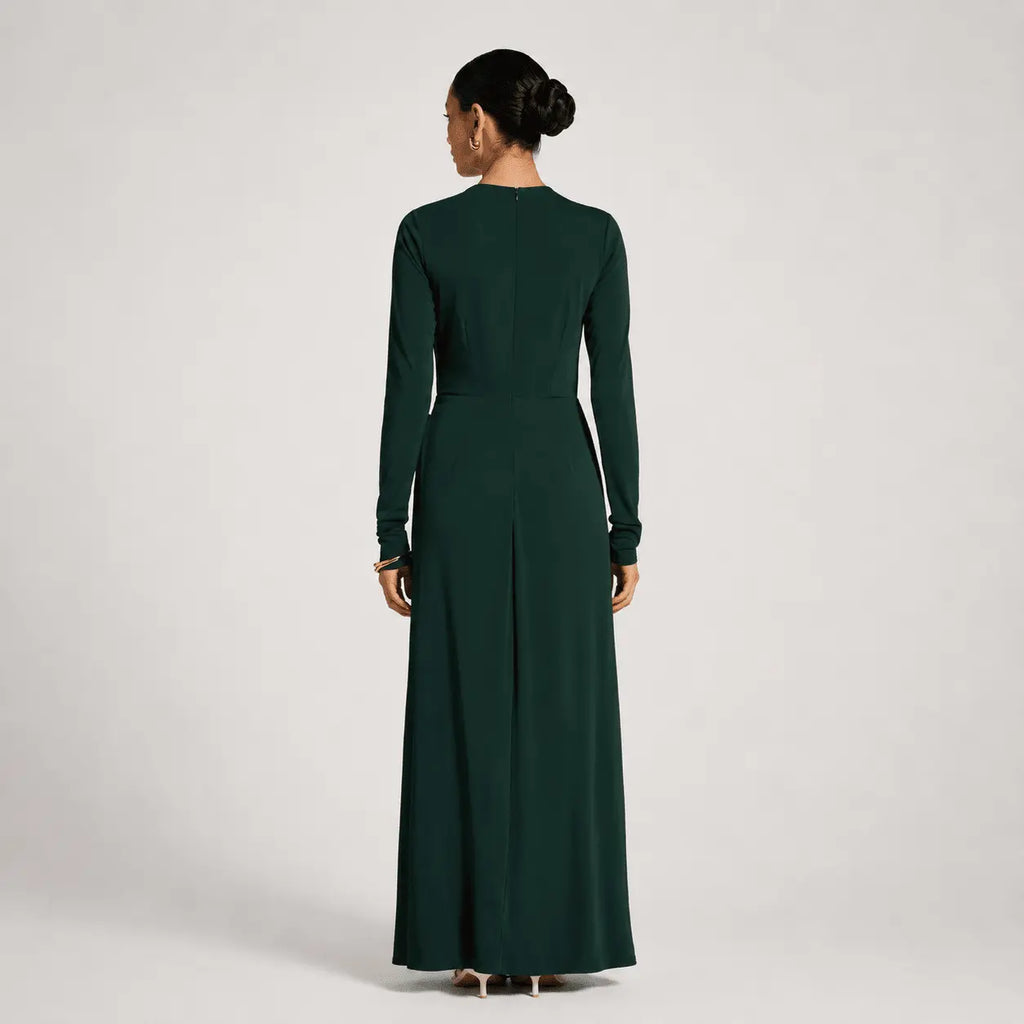 Woman wearing a long dark green dress on a light gray background