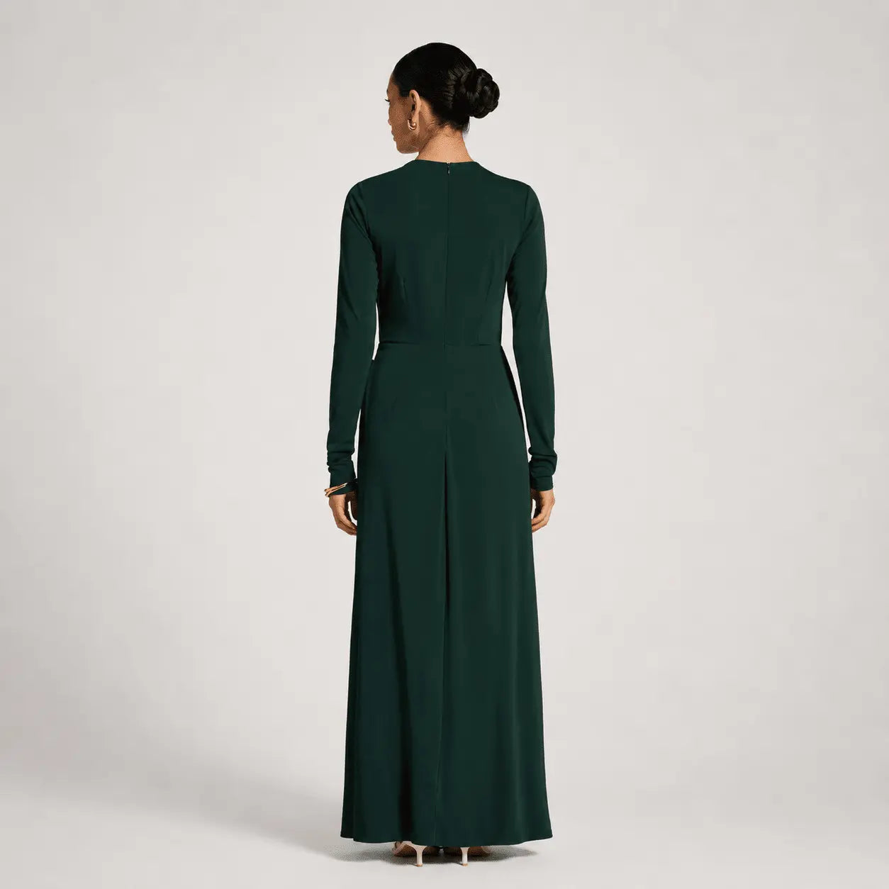 Woman wearing a long dark green dress on a light gray background