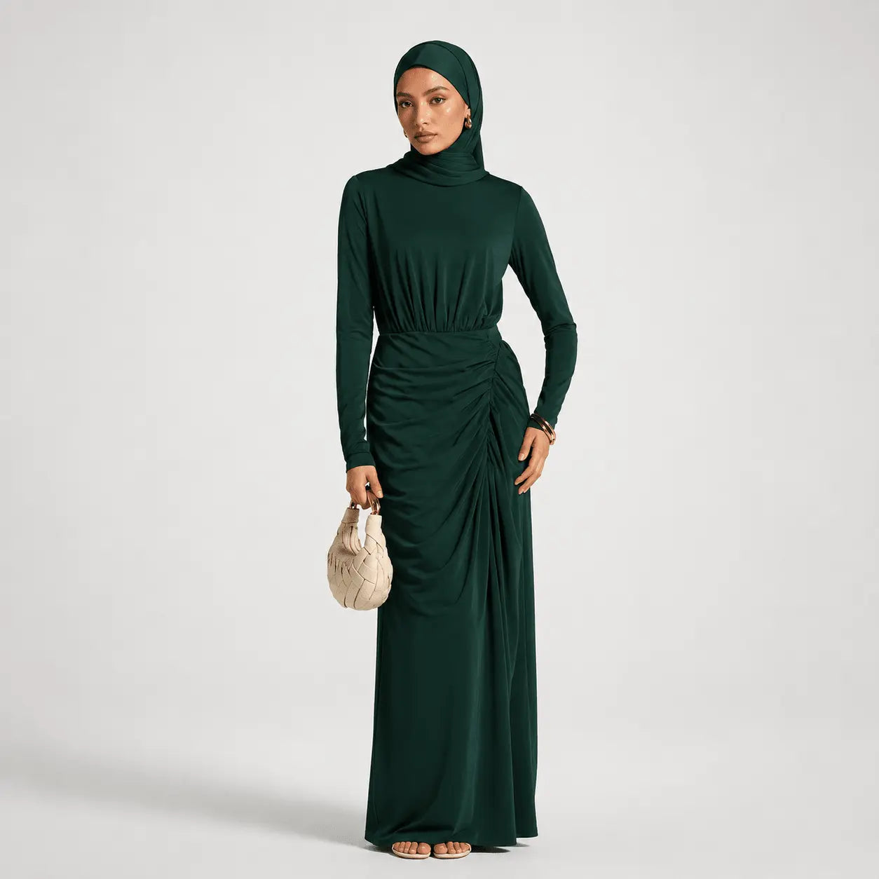 Woman wearing a green long-sleeve dress with a matching hijab on a white background